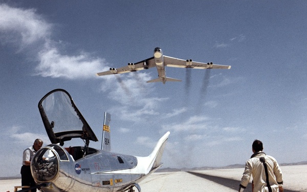 HL-10 on lakebed with B-52 flyby