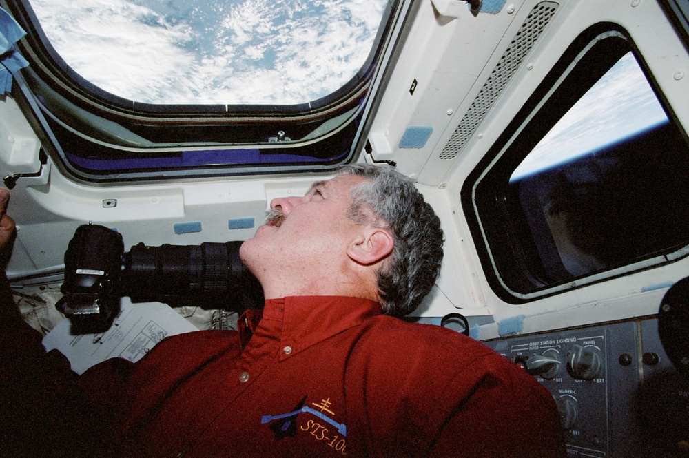 MS Phillips looks out of an overhead window on the flight deck of Endeavour during STS-100