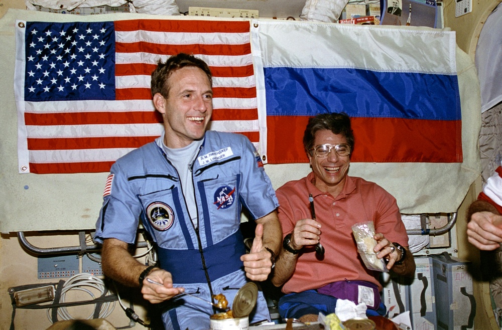 STS-81 and Mir 22 crew share a meal in the Mir space station Base Block