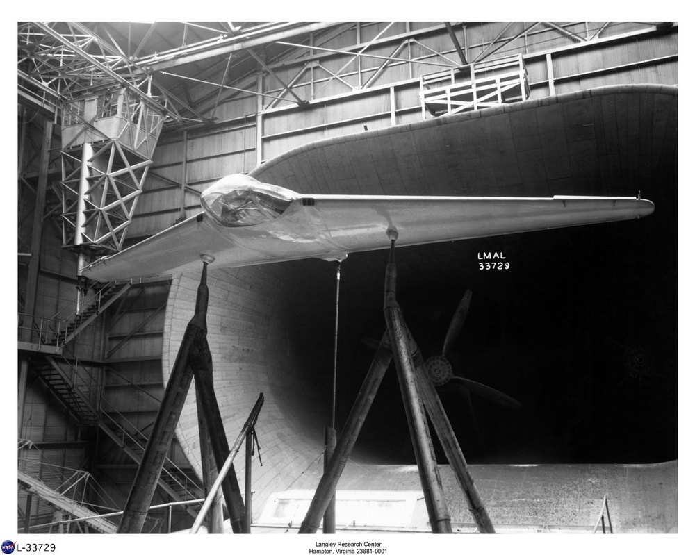 A black-and-white archival photograph from NASA's Langley Research Center showing a flying wing or tailless aircraft model mounted on a support structure inside a large wind tunnel test section. The model appears to be a swept-wing design with a central cockpit/fuselage blister, positioned facing the wind tunnel opening. The image is labeled LMAL 33729, corresponding to the Langley Memorial Aeronautical Laboratory catalog number.