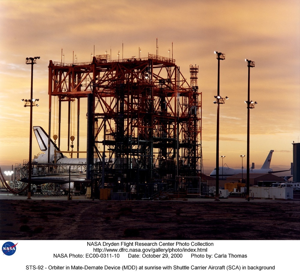 STS-92 - Orbiter in Mate-Demate Device (MDD) at sunrise with Shuttle Carrier Aircraft (SCA) in backg