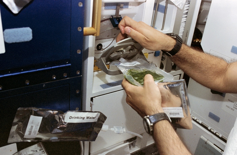 Astronaut Guidoni prepares a meal at the shuttle galley