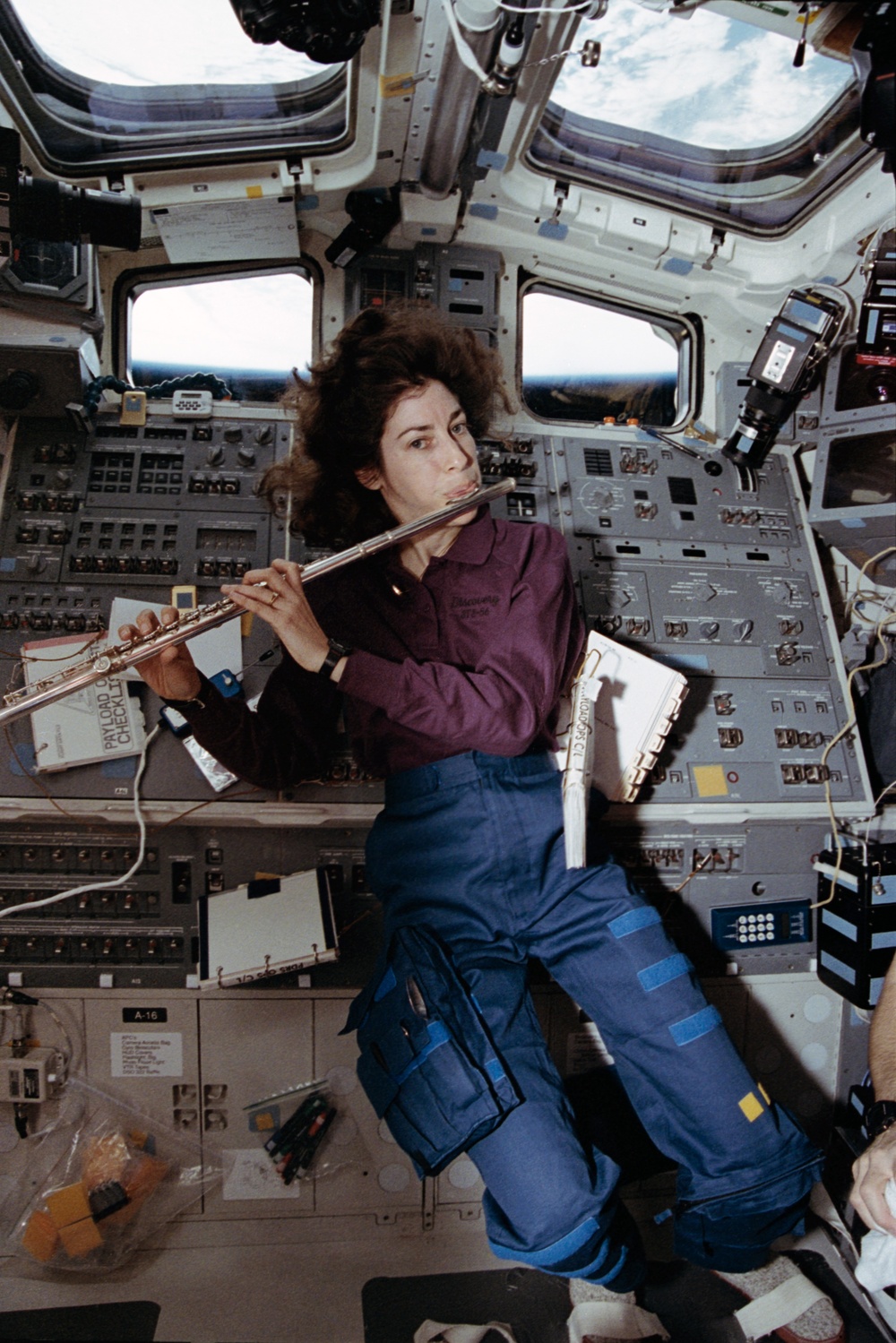 Candid view of a crewmember playing a flute in the aft flight deck.