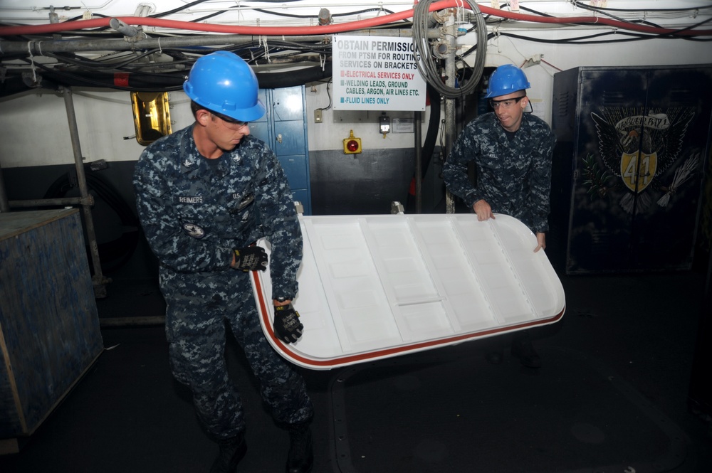 Sailors carry watertight door during ship refurbish