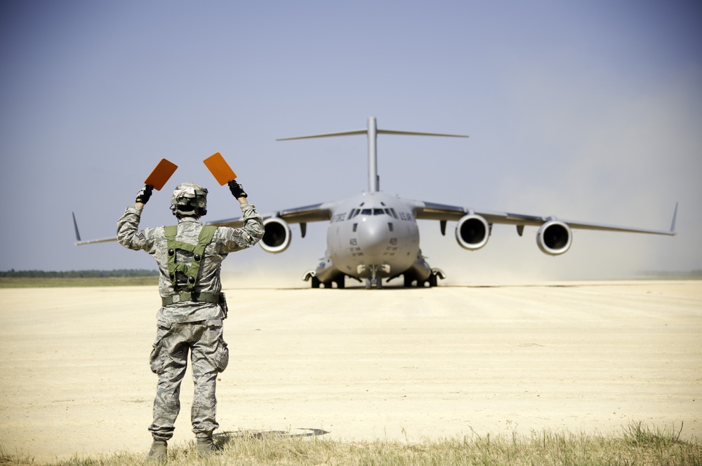 Service member guides C-17 onto landing zone