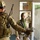 A Kentucky soldier helps with security in southern Afghanistan Two U.S. Army soldiers in MultiCam (OCP) camouflage uniforms are inside what appears to be an Afghan government or security building. The soldier in the foreground is identified by a name tape reading 'MORENO' and wears a helmet with eye protection. The second soldier, a female, wears a green hijab/headscarf over her helmet and has 'U.S. ARMY' visible on her uniform.