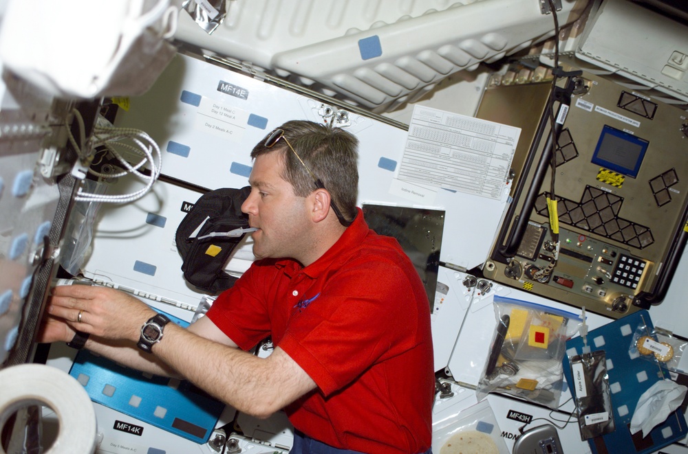 Pilot Frick gets a drink at the galley on the middeck of Atlantis during STS-110