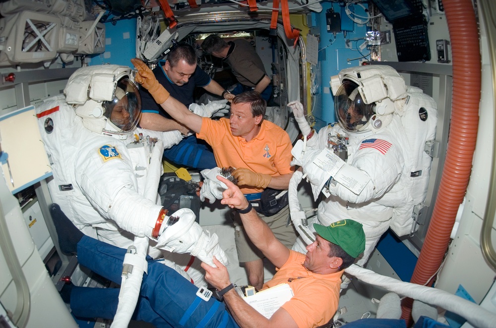 STS-116 Crewmembers Curbeam and Williams are removing their EMUs after spacewalk