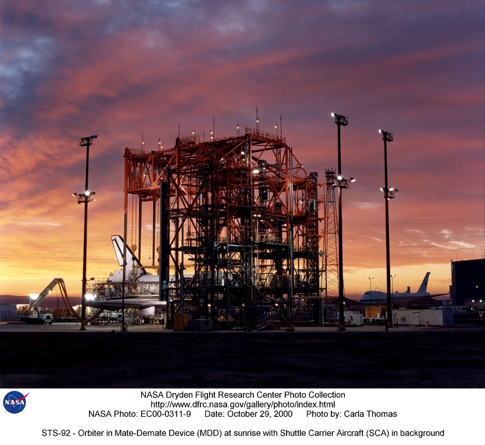 STS-92 - Orbiter in Mate-Demate Device (MDD) at sunrise with Shuttle Carrier Aircraft (SCA) in backg