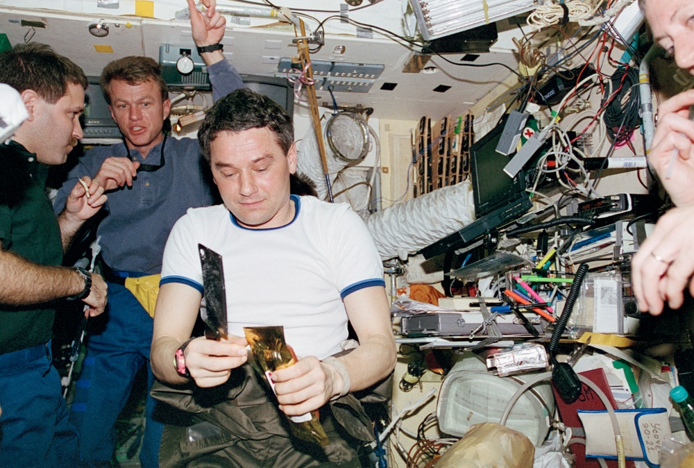 STS-81 and Mir 22 crew share a meal in the Base Block module