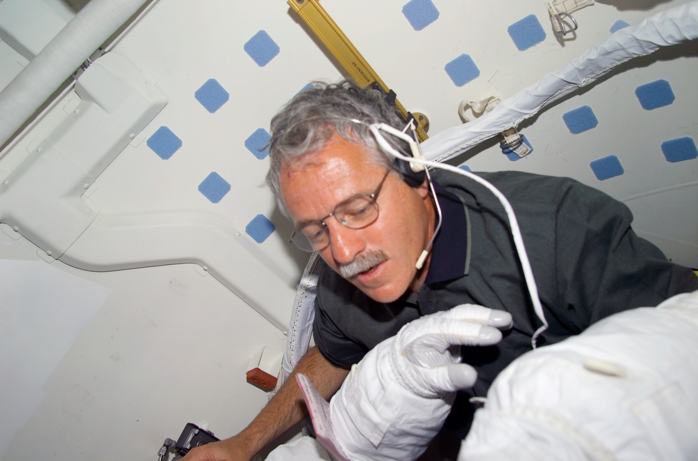 MS Phillips helps a fellow crewmember with his EMU before the first EVA of STS-100