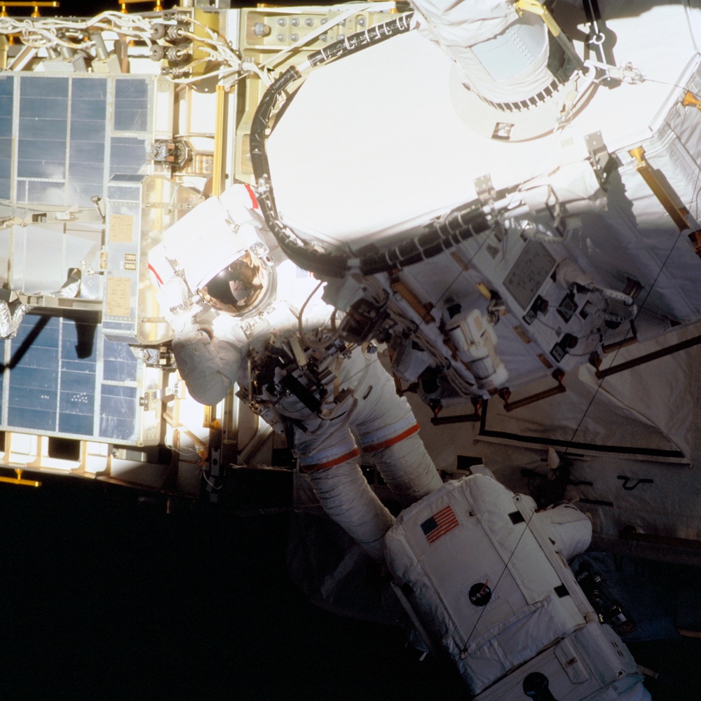 Forrester places Barry's EMU booted feet into foot restraint on ISS P6 truss