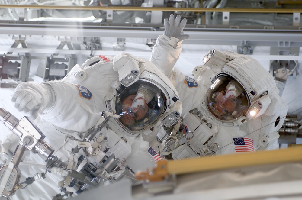 Walheim and Smith wave to fellow crewmembers during the third EVA of STS-110