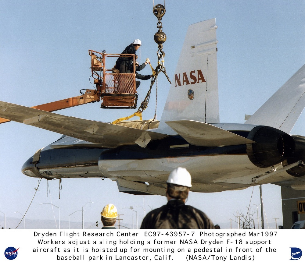 Retired NASA F-18 being hoisted up by crane to pedestal mount at Lancaster California Municipal Base