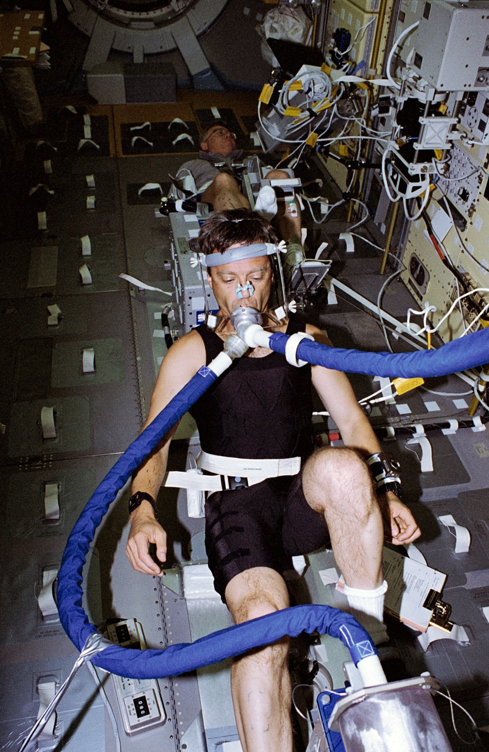 ALFE, Thirsk exercises on Spacelab ergometer as Helms monitors