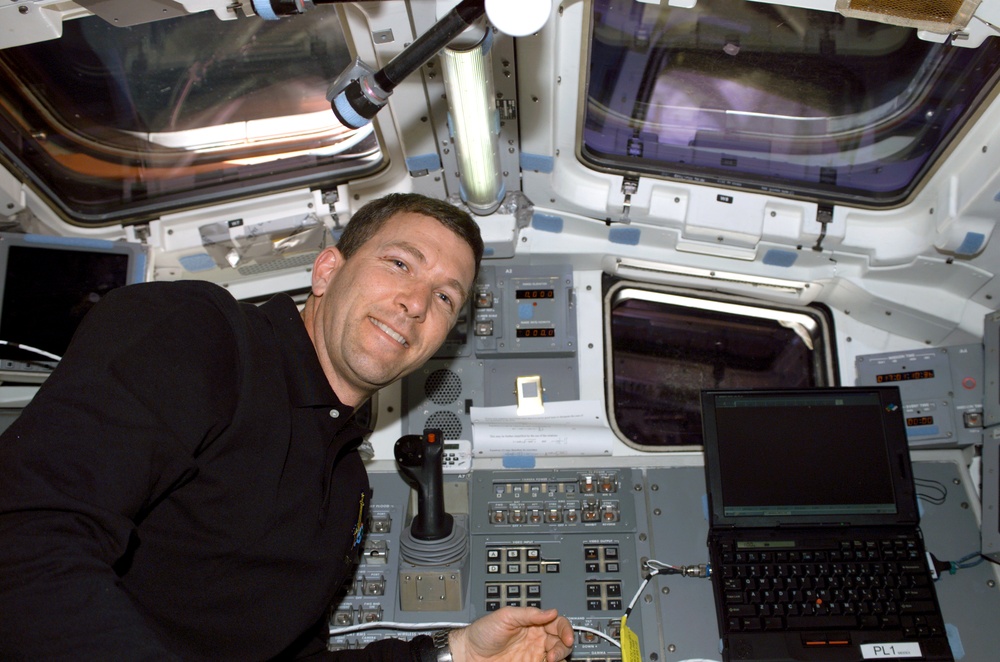 Husband smiles for the camera beside Columbia's AFD control panel during STS-107