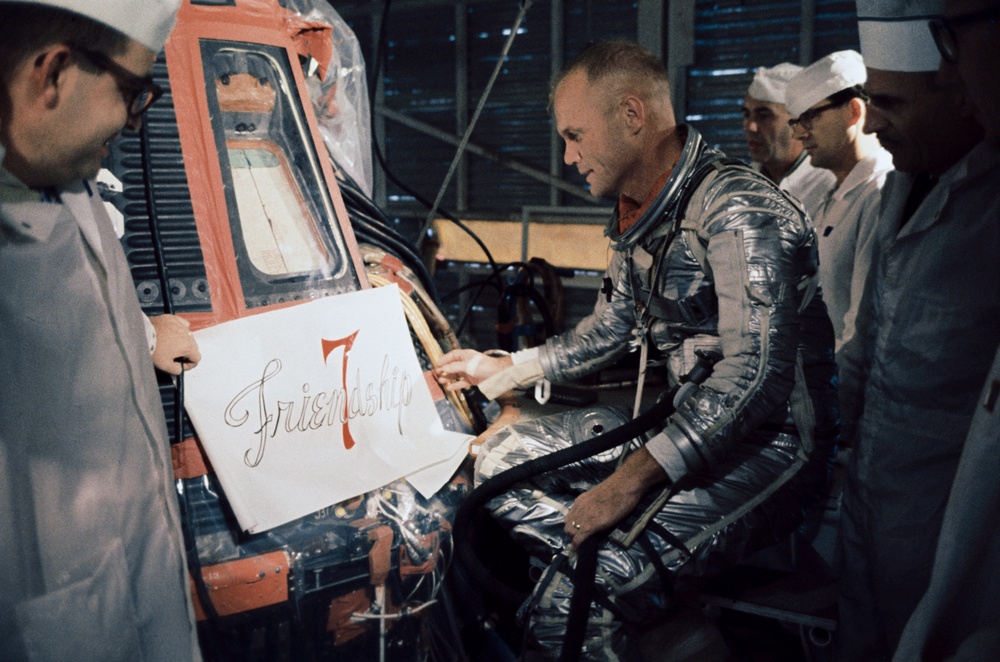 Astronaut John Glenn inspects decal for side of his Mercury capsule