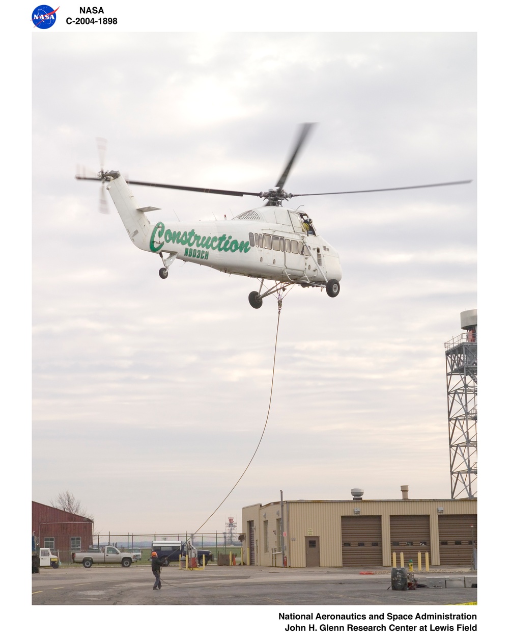 Helicopter being used to lift air conditioner units up to the roof of buiding 50