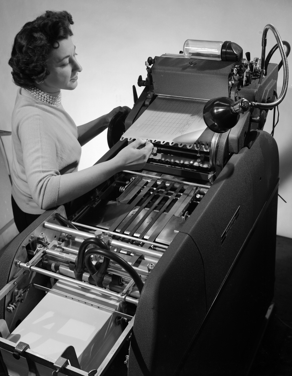 OPERATOR RUTH GUARNIERI PUTTING PLATE ON MULTILITH PRESS FOR REPRODUCTION OF REPORT FIGURES
