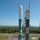 A Boeing Delta II rocket is shown on the launch pad, marked with NASA and STEREO mission insignia, at what appears to be Cape Canaveral Air Force Station in Florida. The rocket is painted in its characteristic teal/white color scheme and is surrounded by launch support infrastructure. Ground crew personnel are visible near the base of the rocket.