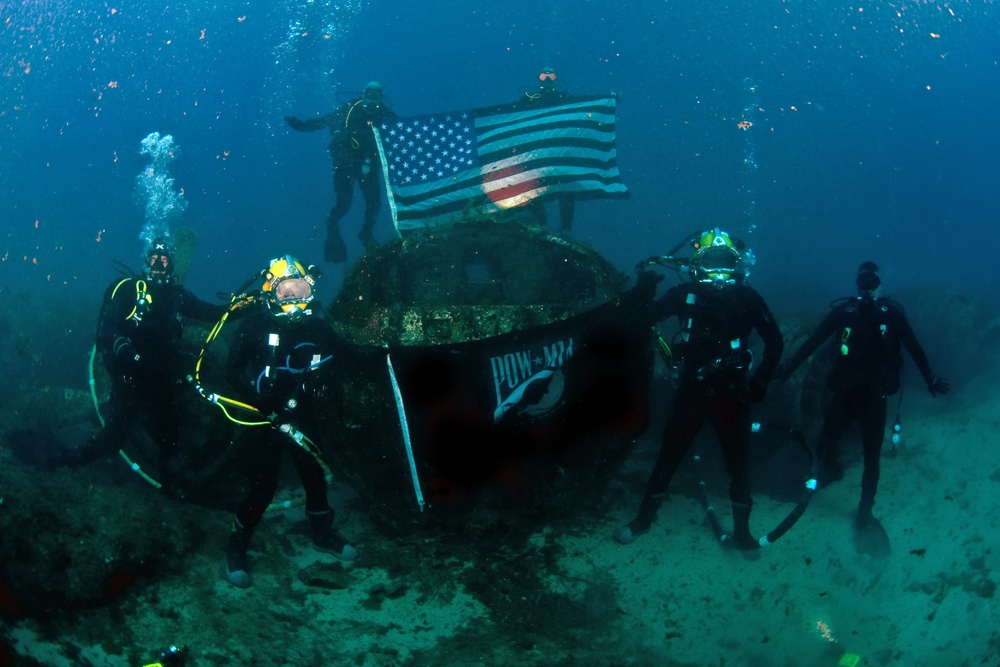 US Navy divers, alongside the Joint POW/MIA Accounting Command, search for an unaccounted-for service member who went missing during World War II