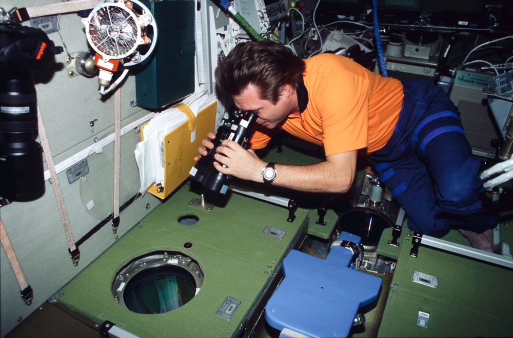 Onufrienko uses binoculars to look out SM window during Expedition Four