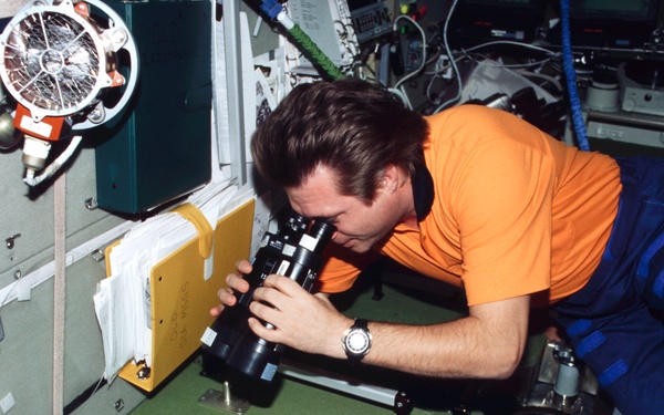 Onufrienko uses binoculars to look out SM window during Expedition Four