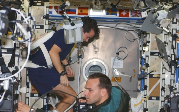 Shuttleworth works in U.S. Lab as Bursch exercises on cycle Ergometer during Expedition Four