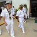 A group of naval officers in white dress uniforms are walking together outside what appears to be an official building or conference venue. The officers appear to represent multiple nations, suggested by the varying cap insignia and medal ribbons visible on their uniforms. The scene suggests a formal military meeting, ceremony, or diplomatic event.