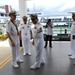 A group of naval officers in white dress uniforms are gathered at what appears to be a Philippine Navy facility, visible from the text 'The Future of the Philippine Navy' on a vessel or banner in the background. One officer appears to be gesturing and briefing or directing another senior officer, suggesting an official visit or inspection. A photographer is capturing the event in the background.