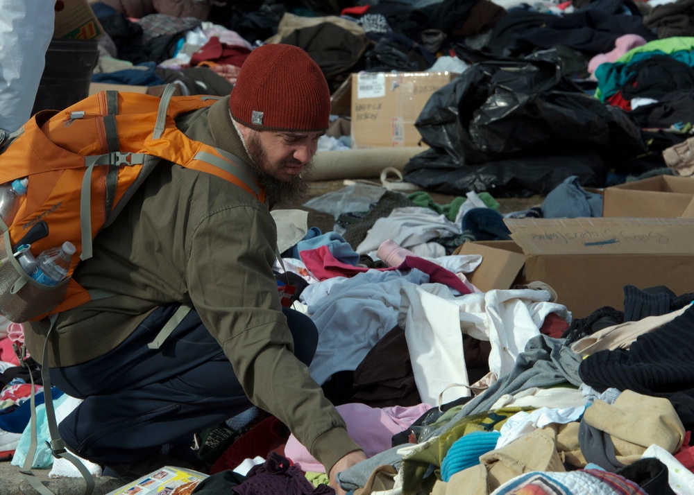 Displaced civilian searches for clothing.