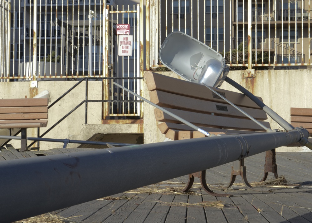 A Displaced light pole rests on a Long Beach Pier bench