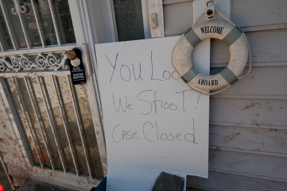 A sign warning looters to 'beware' is posted on the front door of a flooded home in Long Beach, NY