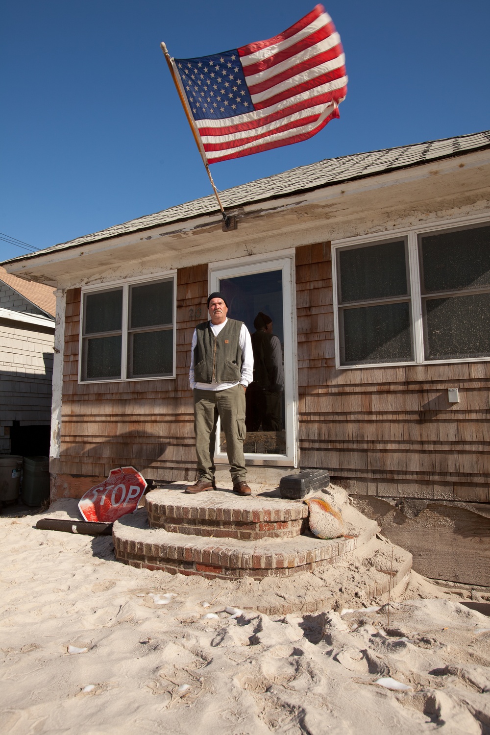 Hurricane Sandy survivor stands on the porch of his flooded home in Long Beach, NY