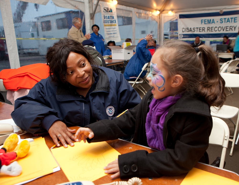 FEMA Community Relations worker listens to young hurricane survivor in a Disaster Recovery Center