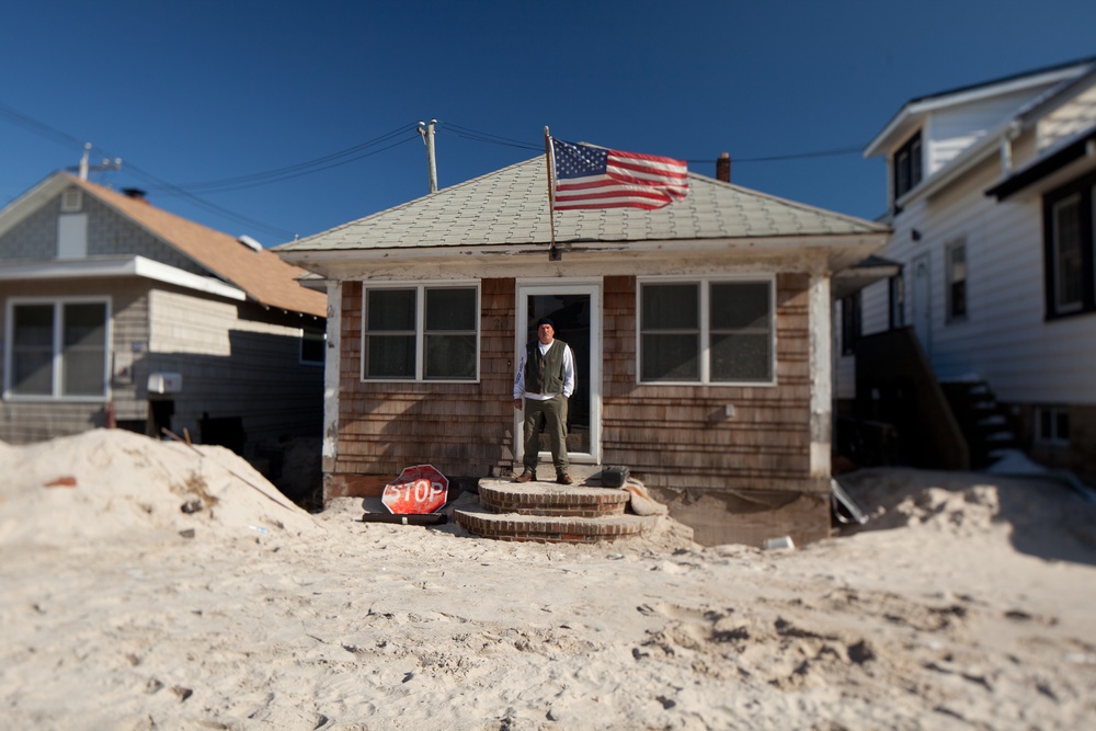 Hurricane Sandy survivor stands on the porch of his flooded home in Long Beach, N.Y.