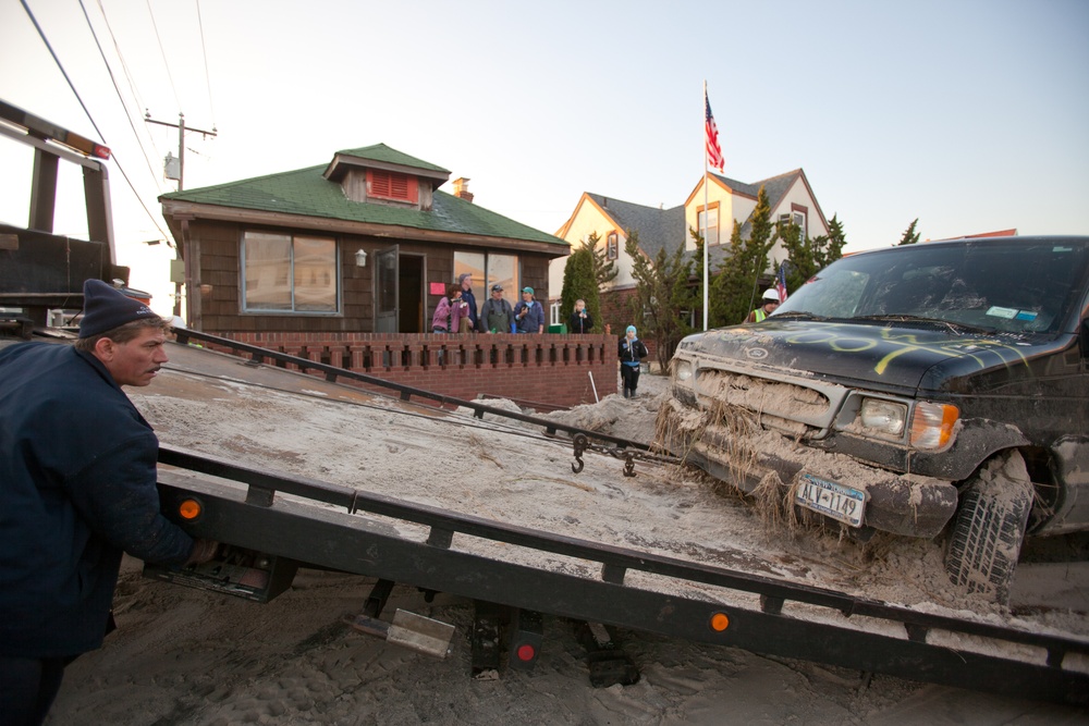 Vehicle destroyed by Hurricane Sandy storm surge is removed by tow trailer from Long Beach, New York.