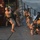MARSOC conducts VBSS training with 160th SOAR Military personnel in combat gear are conducting a breach training exercise on what appears to be the deck of a ship. Sparks are visible near a shipping container marked 'APL' with the word 'BREACH' spray-painted in green, indicating an active breaching operation. The scene takes place on an open deck with ocean water visible in the background.