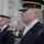 Presidential Inaugural Parade The image shows military or law enforcement personnel in formal dress uniforms standing at attention, likely during a parade or ceremonial event. The foreground subject wears a dark navy uniform with a visible 'Honor Guard' tab on the shoulder and a service cap with gold trim. The setting appears to be an urban street with a crowd of spectators visible in the background.
