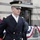 Presidential Inaugural Parade A U.S. Army officer in dress blues uniform stands at attention during what appears to be a formal military ceremony or parade. The setting includes patriotic bunting decorations in red, white, and blue, suggesting a national event or holiday observance. The background shows an urban street environment with spectators and barriers.