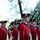 Presidential Inaugural Parade A formation of soldiers dressed in 18th-century Continental Army-style uniforms — red coats with navy blue facings, white breeches, and tricorn hats with white trim — stand at attention near the U.S. Capitol building in Washington, D.C. The soldiers appear to be members of a ceremonial military unit, likely the U.S. Army Old Guard Fife and Drum Corps or a similar historic reenactment unit. The scene suggests a formal ceremonial event or parade near Capitol Hill.