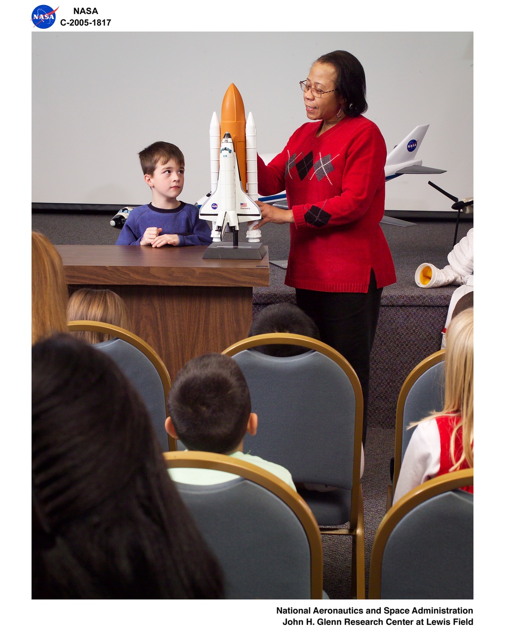 NASA Glenn Visitor Center, Auditorium, Speaker's Bureau member shows visitors a scale model of the Space Shuttle in launch configuration during an auditorium presentation