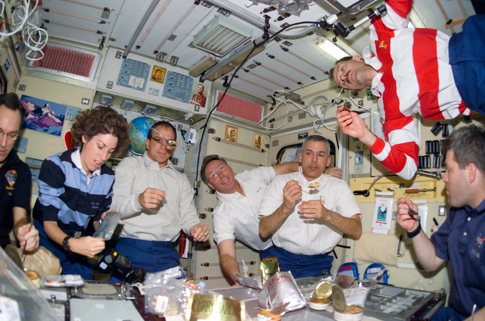 STS-110 and Expedition Four crewmembers gather for a meal in the Zvezda SM