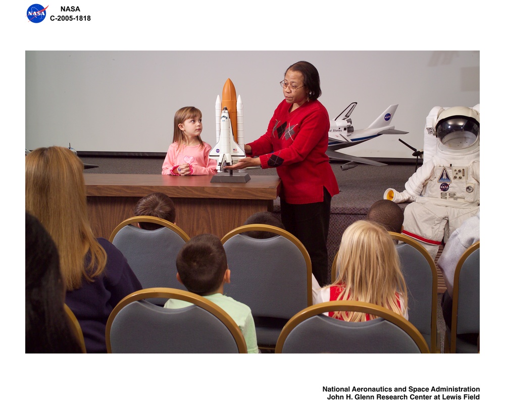 NASA Glenn Visitor Center, Auditorium, Speaker's Bureau member shows visitors a scale model of the Space Shuttle in launch configuration during an auditorium presentation