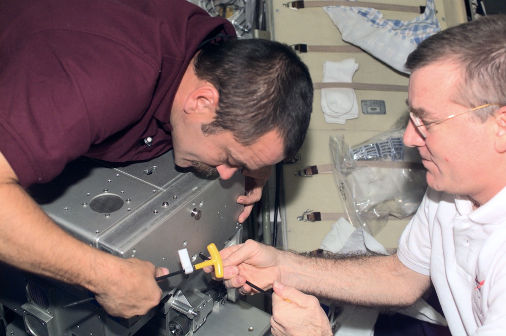 Tyurin and Voss perform maintenance on the TVIS treadmill in the Service Module