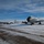 108th Wing removes snow from winter storm Nemo Two U.S. Air Force aircraft, identifiable as KC-135 Stratotanker aerial refueling tankers, are parked on a snow-covered flight line at a military airbase. The foreground aircraft displays 'U.S. AIR FORCE' markings and what appears to be '108 WING' text on the engine nacelle. Winter conditions are evident with snow covering the tarmac and surrounding terrain under a partly cloudy blue sky.