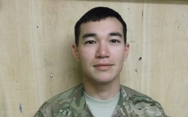 A U.S. Army soldier in MultiCam (OCP) camouflage uniform is photographed against a plywood wall background. The soldier's name tape reads 'ROWELL' and the branch tape reads 'U.S. ARMY'. A reversed American flag patch is visible on the left sleeve, consistent with U.S. military uniform regulations.