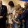 Hawaii State Medal of Honor ceremony pays tribute to fallen service members A group of adults and a child are gathered in what appears to be a formal or ceremonial setting, possibly a church or memorial service. A man in a blue suit is leaning down to embrace or console a young child, while others stand nearby in somber or reflective postures. The atmosphere suggests a solemn occasion such as a funeral, memorial, or formal ceremony.