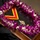 Hawaii State Medal of Honor ceremony pays tribute to fallen service members A formal ceremonial display featuring a red and yellow ribbon collar with a decorative medallion/badge, arranged on a glass-topped wooden tray. The display is adorned with a traditional Hawaiian lei made of purple and white orchids. A white satin bow is also visible, suggesting this is a presentation or commemorative arrangement.