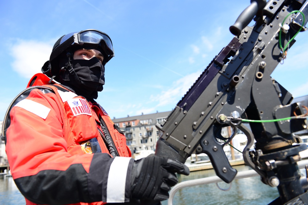 A Coast Guard Station crew member mans the gun mount in the Boston Harbor